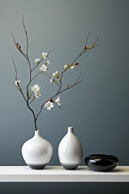 Bílá váza s větvičkou s květinami.